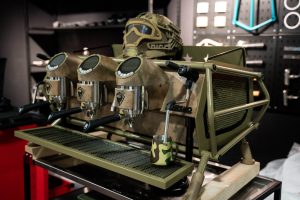 Fully customized Sanremo Café Racer commercial espresso machine with military camo finish and triple group heads, designed to stand out in high-end cafés seeking bold, personalized coffee equipment.