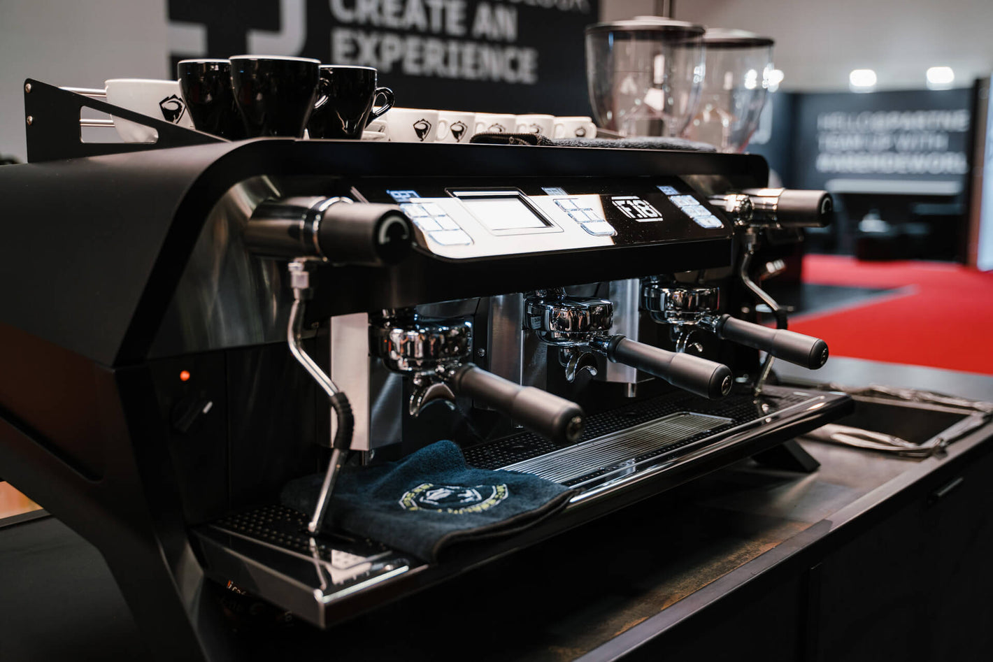 Sanremo F18 3 groups black commercial espresso machine 3/4 view, at a coffee industry event