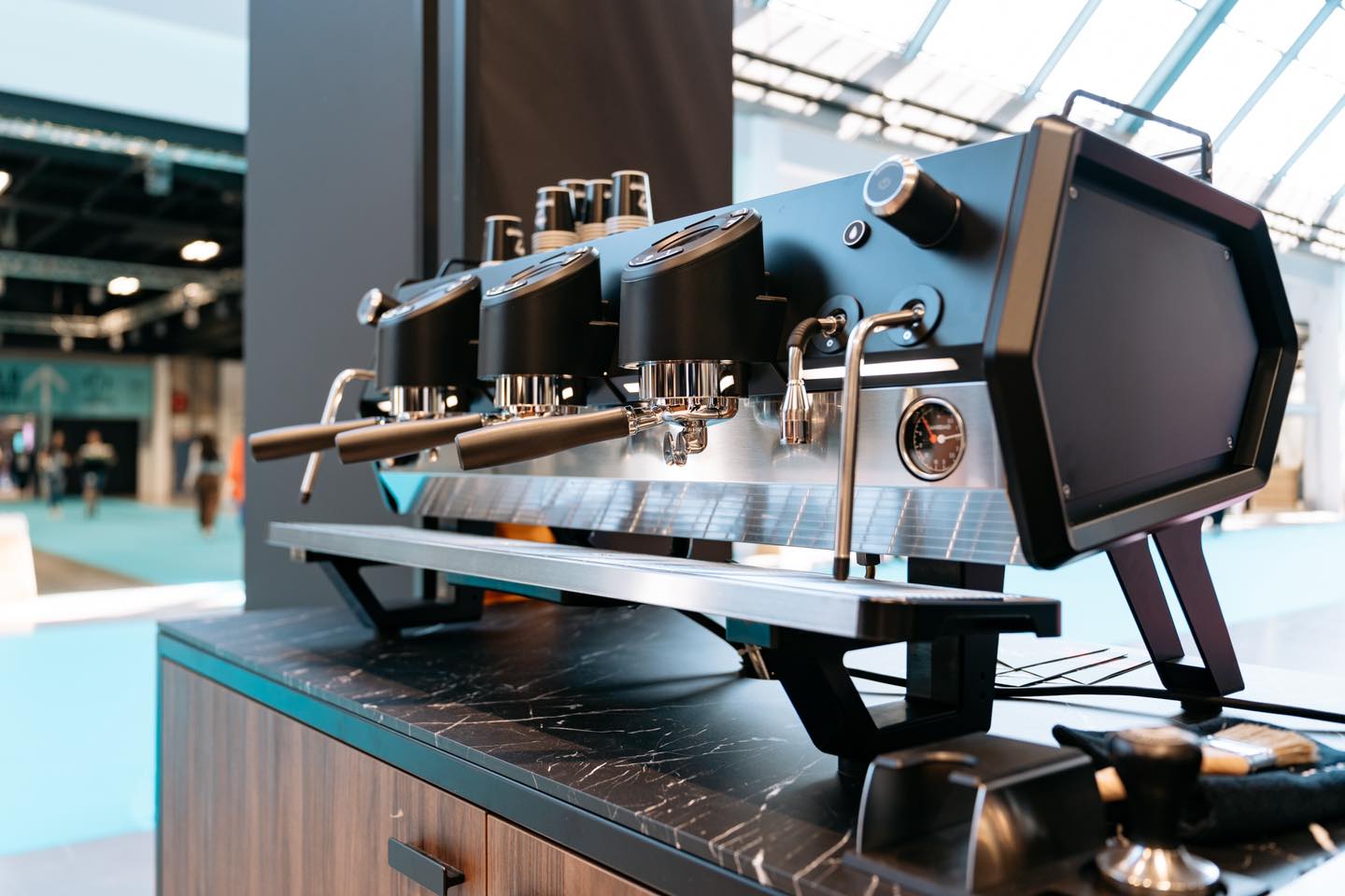 Sanremo D8 3 Group black espresso machine on café bar, angled 3/4 view