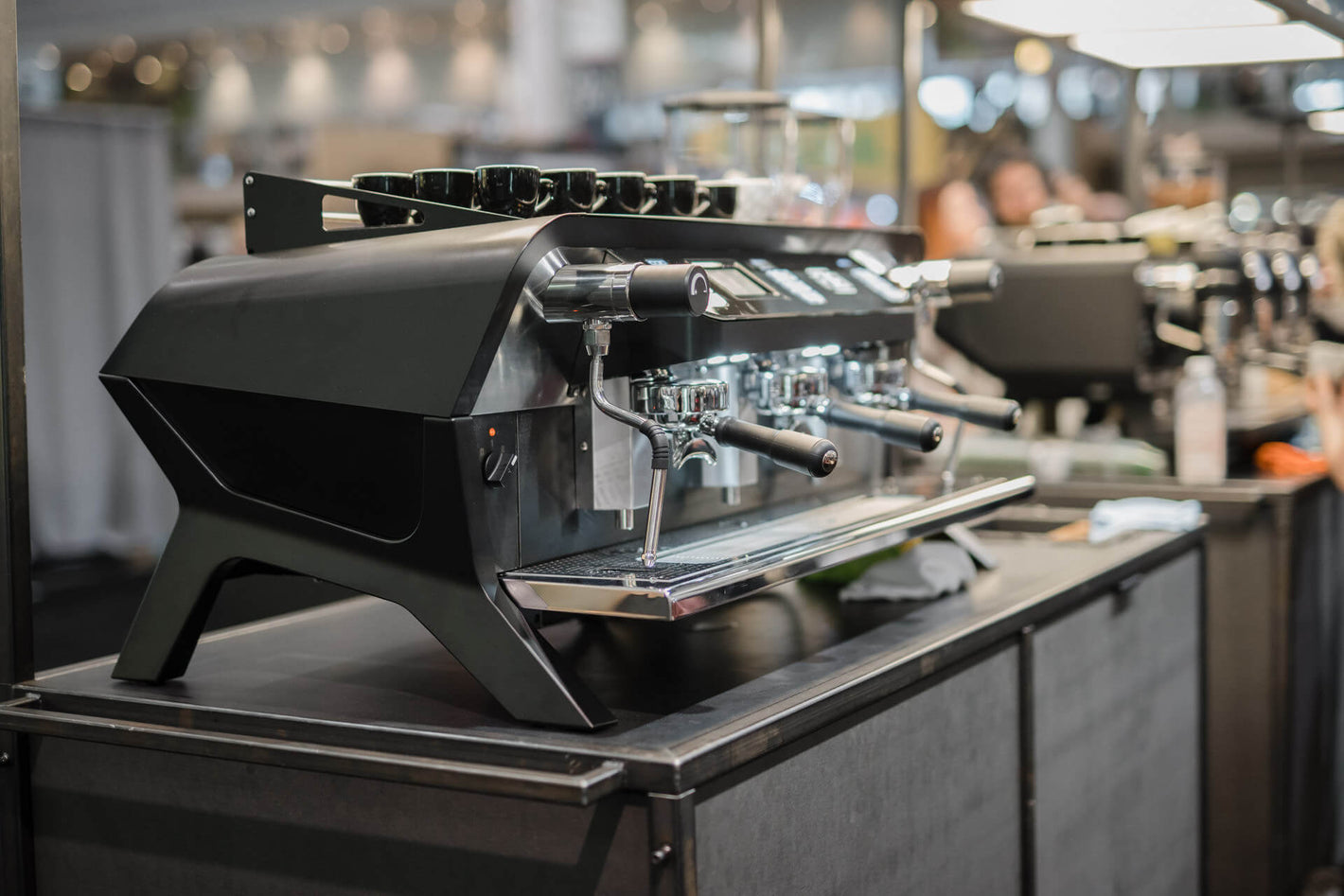 Sanremo F18 3 groups black commercial espresso machine 3/4 view, at a coffee industry event