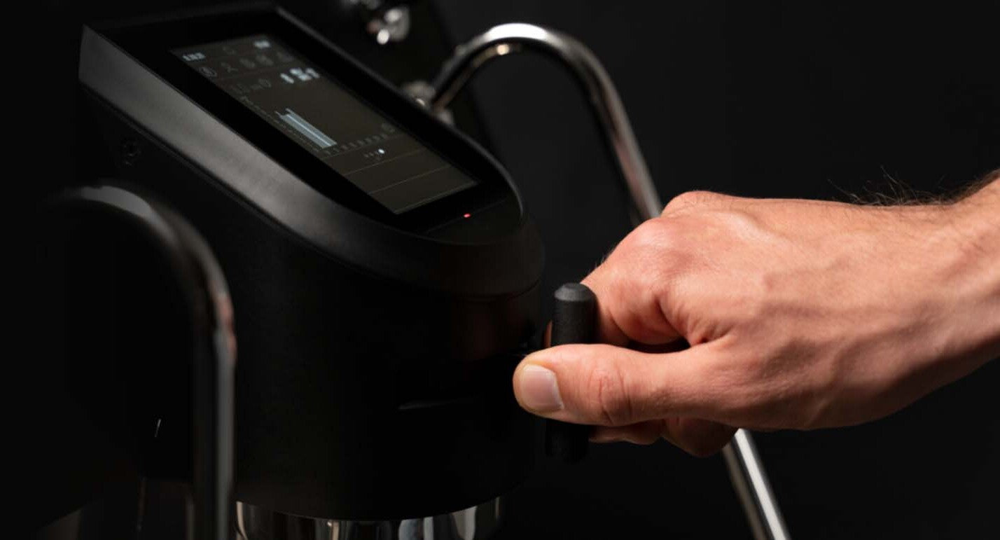 Barista adjusting the brewing lever on the Sanremo YOU espresso machine, showcasing the precision touchscreen interface designed for advanced brew profiling and workflow efficiency for home coffee connoisseurs.